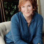 A smiling woman with short red hair and a blue shirt