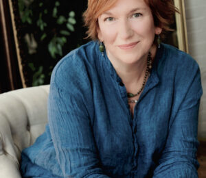 A smiling woman with short red hair and a blue shirt